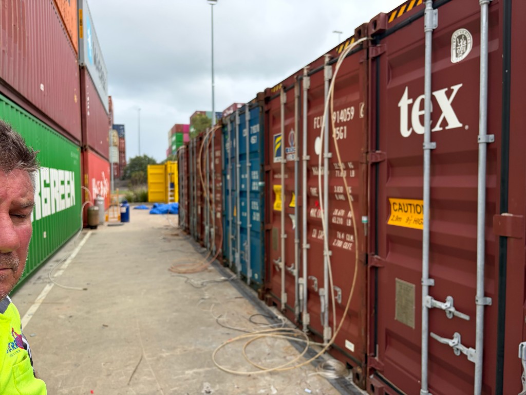TFS crew fumigating a line of shipping containers at a container yard