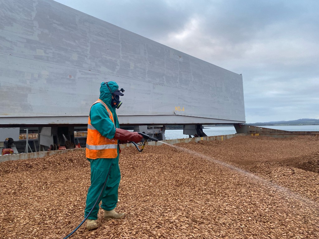 TFS fumigator spraying the surface of a loaded No. 4 woodchip hold